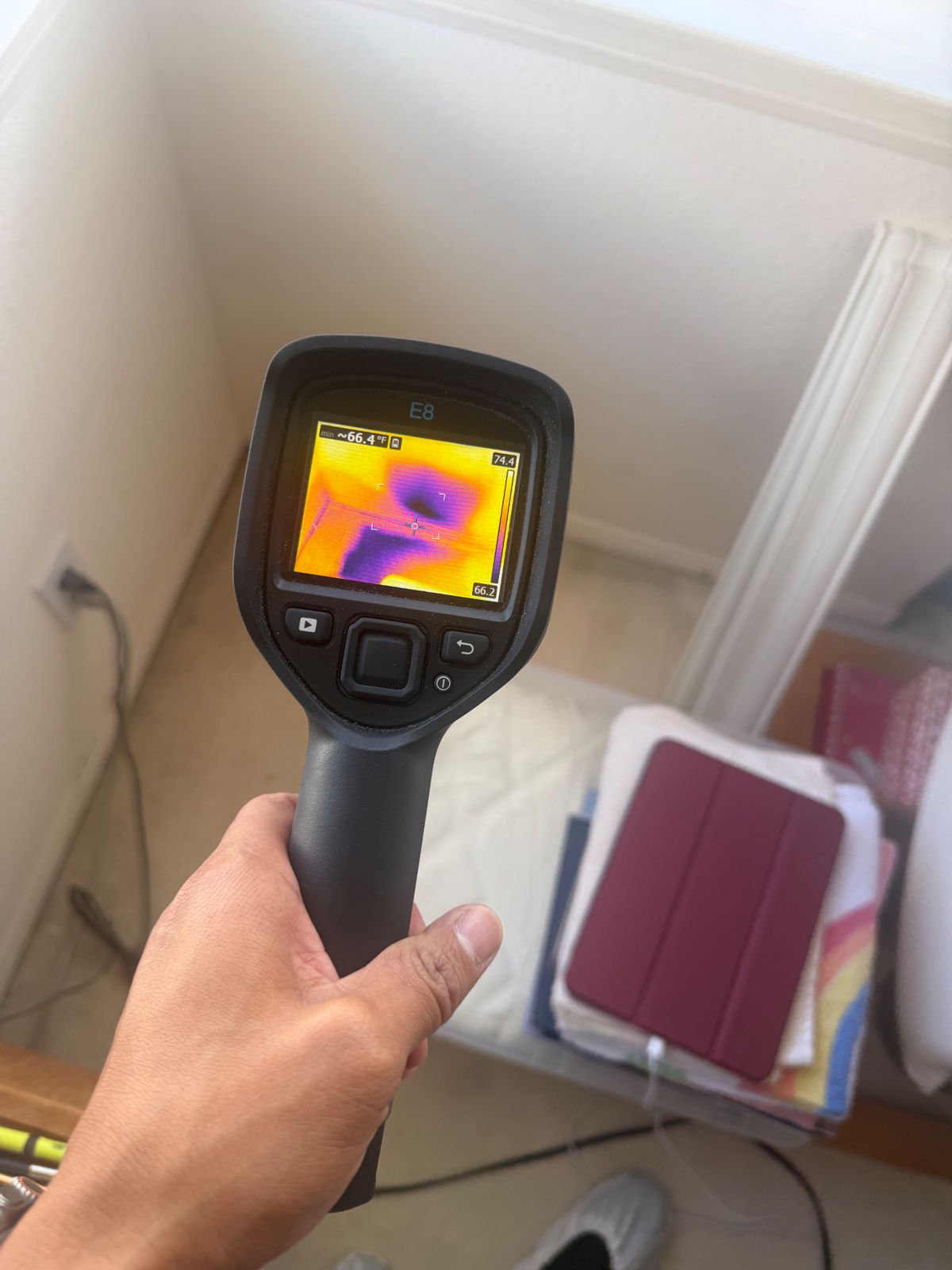 Inspector holding a thermal imaging camera in a San Diego home closet